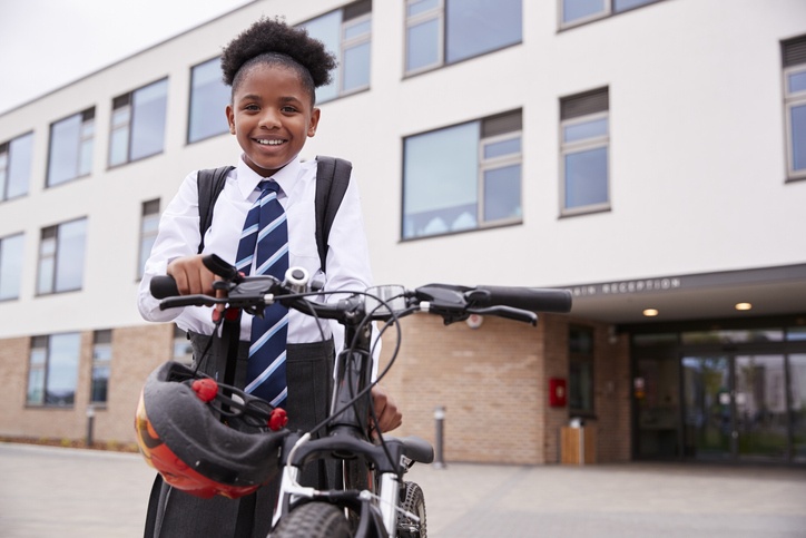 girl wheeling her bicycle away from school
